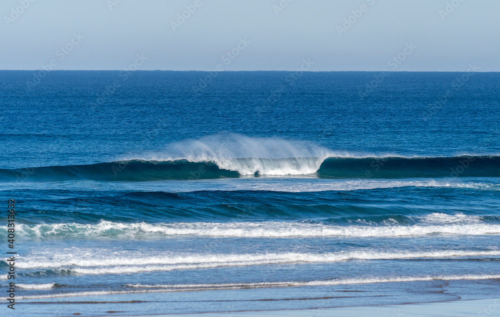 Wave breaking on a bright sunny morning. Perfect wave barrel with offshore wind on a sand beach break Wave breaking on a bright sunny morning. Perfect wave barrel with offshore wind on a sand beach break