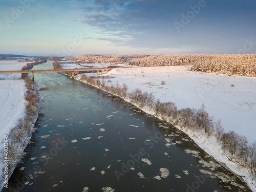 Fototapeta Naklejka Na Ścianę i Meble -  Bridge over the Dnieper River, snowy forest on a beautiful winter day with blue sky and clouds. Beautiful winter landscape