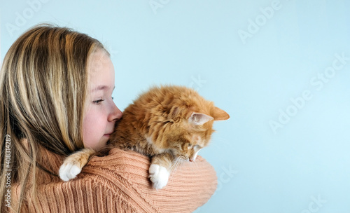 Girl holds her cat on shoulder on blue background. Copy space. Banner