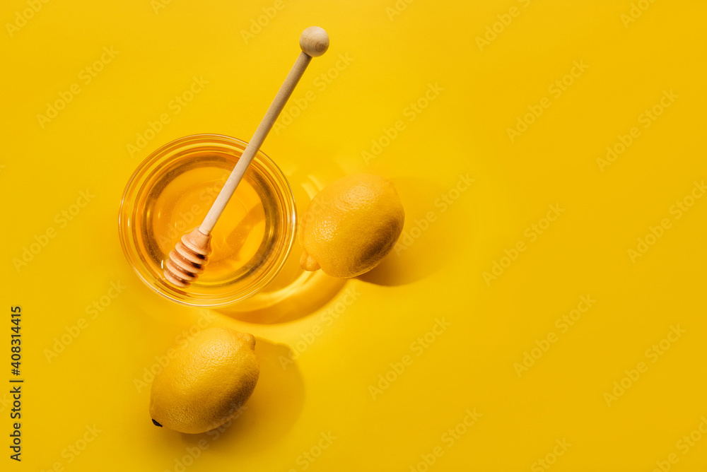 Cup with honey and lemons on a yellow background. Cup with honey and lemons on a yellow background.