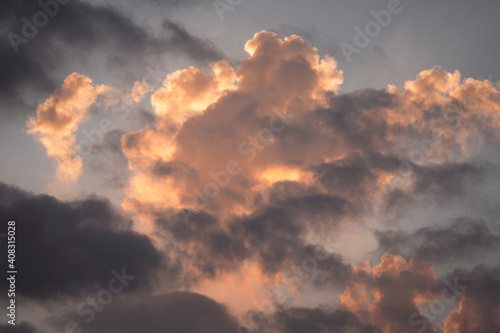 Scenic sunrise cloudscape with orange fluffy clouds. Scenic dawn sky with orange and grey cumulus.