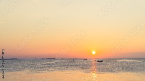 Sunset sky over sea in the evening with colorful orange sunlight over minimal fishing boat,Dusk sky