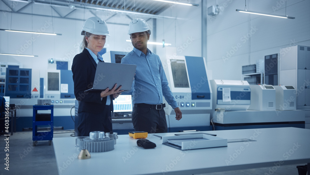 Fototapeta premium Modern Factory with Professional Workers, Engineers, Managers Working on Production Line, Workshop Management, Optimization. Industrial Facility: Equipped with CNC Machinery and Robot arm Technology