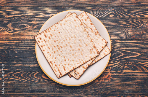 Plate with Jewish flatbread matza for Passover on wooden background photo