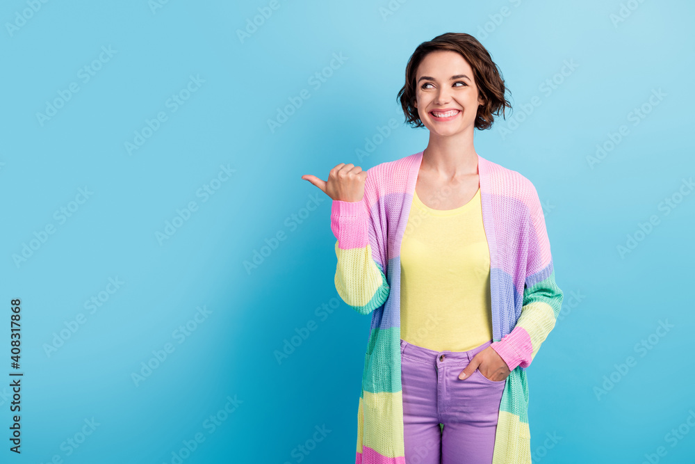Photo portrait of girl pointing thumb looking at blank space isolated on pastel blue colored background Photo portrait of girl pointing thumb looking at blank space isolated on pastel blue colored background
