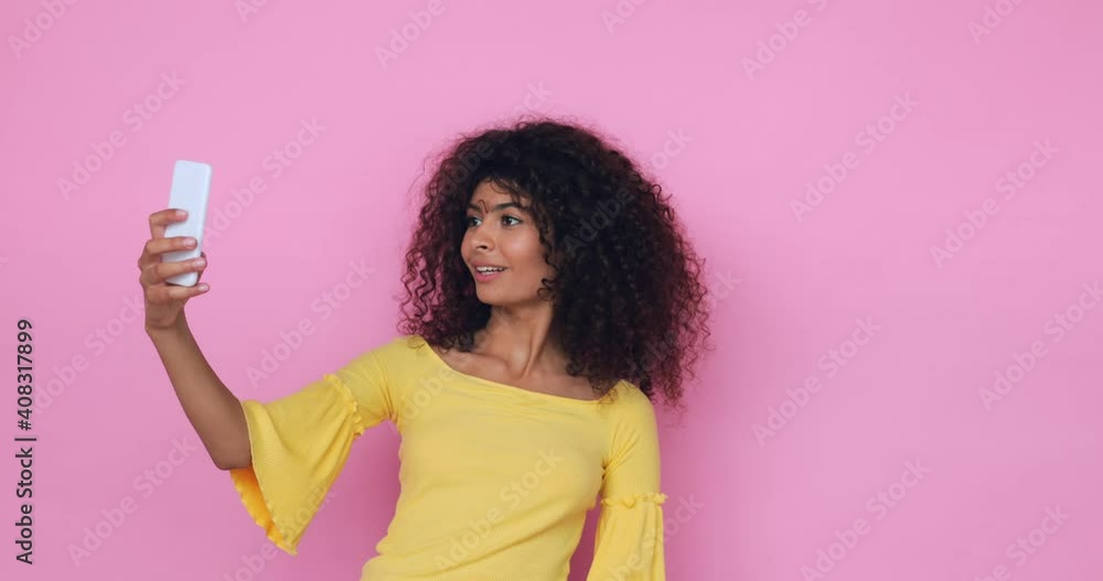 curly young woman taking selfie and using smartphone isolated on pink curly young woman taking selfie and using smartphone isolated on pink