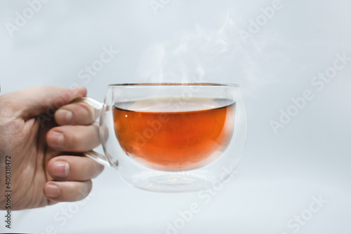 Man's hand holding a transparent cup with tea. Isolated on white background. Alpha