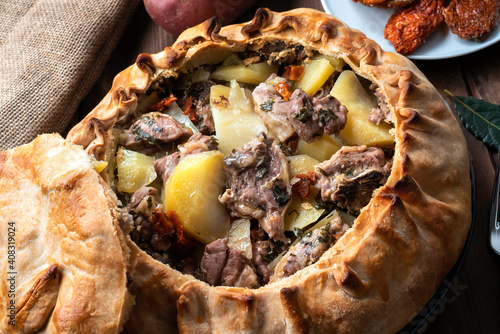 Panada Sarda, pietanza tipica della Sardegna a base di pasta cotta al forno e ripiena di agnello, patate e pomodori secchi, Cucina Italiana  photo