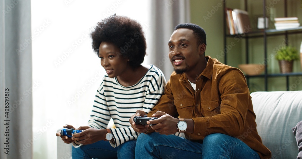 Happy Couple Sitting On The Sofa Playing Video Games Using