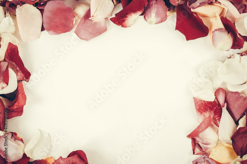 box with ring and rose petal frame on wooden background