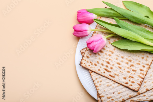 Fototapeta Naklejka Na Ścianę i Meble -  Plate with Jewish flatbread matza for Passover and flowers on color background