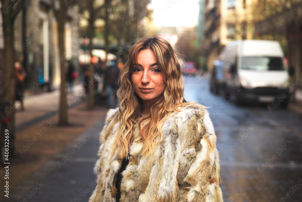 Obraz premium Portrait of a young caucasian blonde woman on the street with a big coat