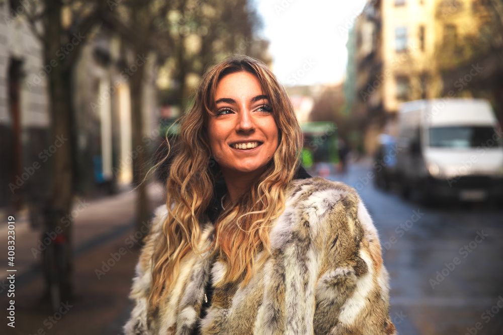 Portrait of a young caucasian blonde woman on the street with a big coat