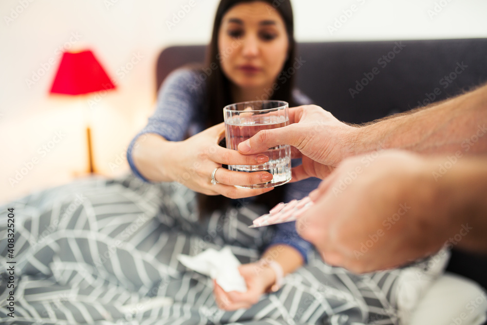 Sick woman with glass water taking pills in bed Sick woman with glass water taking pills in bed