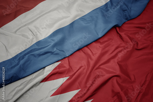 waving colorful flag of bahrain and national flag of luxembourg.