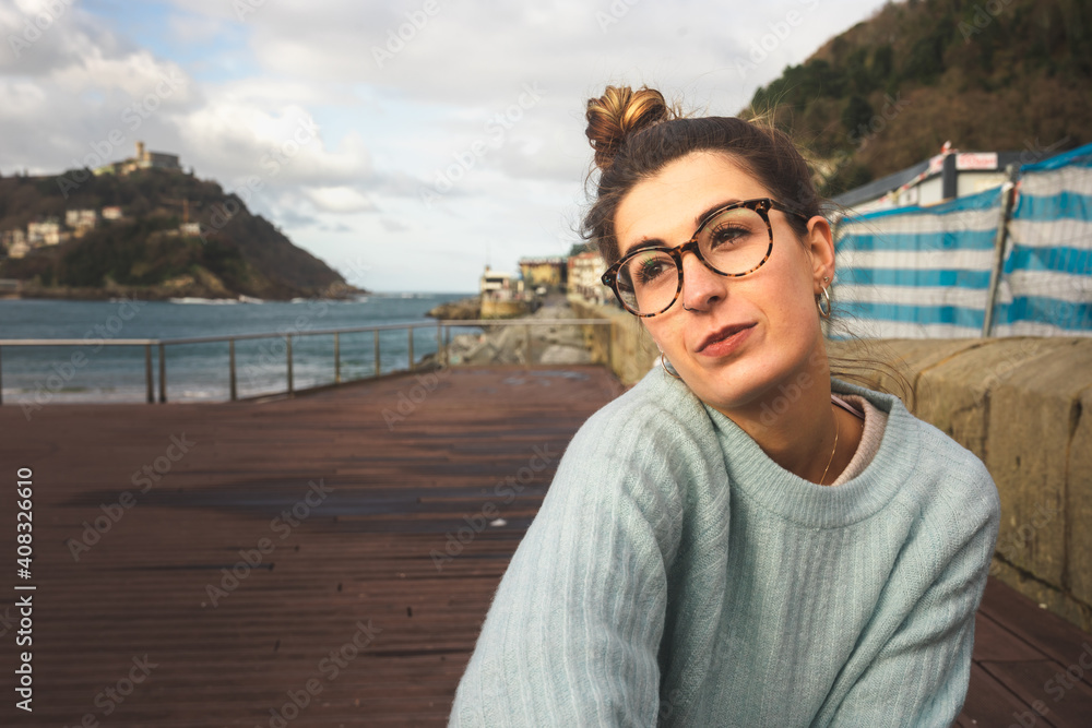 Portrait of a young caucasian girl sat on a bench at the sea side on Donostia-San Sebastian; Basque Country.