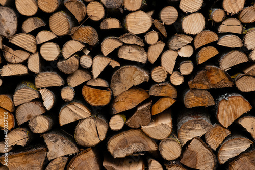 foreground of a pile of split firewood with ends of firewood of different shapes