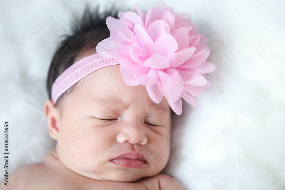 A beautiful newborn girl wearing a pink headband and sleeping on a white soft blanket, Infant, babyhood concept and copy space - Image - obrazy, fototapety, plakaty 