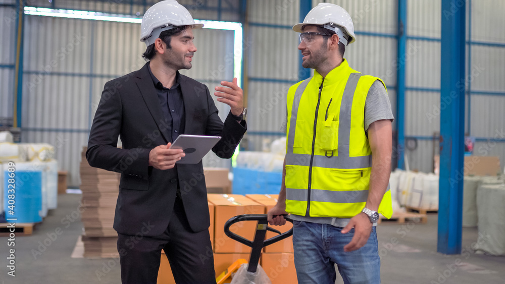 Warehouse worker and manager checking product in a large warehouse Warehouse worker and manager checking product in a large warehouse