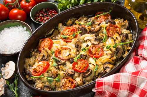 Baked meat with vegetables. Pork, onion, tomato and mushrooms baked in the oven.