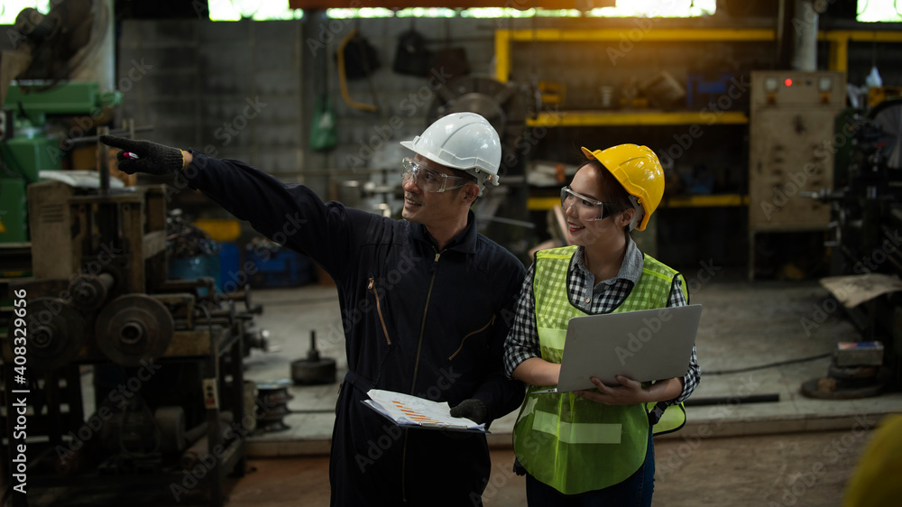 Male and Female Industrial Engineers Talk with Factory Worker while Using Laptop. They Work at the Heavy Industry Manufacturing Facility. Male and Female Industrial Engineers Talk with Factory Worker while Using Laptop. They Work at the Heavy Industry Manufacturing Facility.