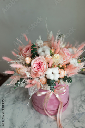 A bouquet of flowers of pink shades of roses and dried flowers in a gift box.