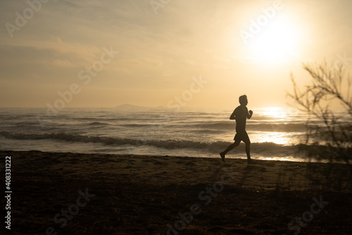 silhouette man run on beach with sunrise and sea background