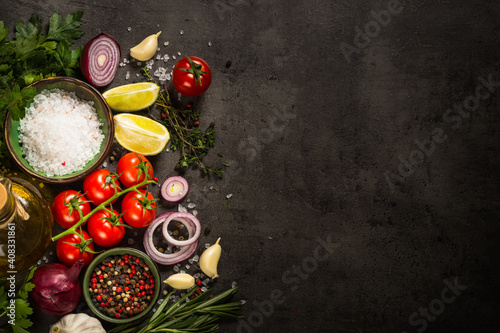 Food background on black slate table. Ingredients for cooking food - tomatoes, onion, spices and herbs. Top view with copy space.