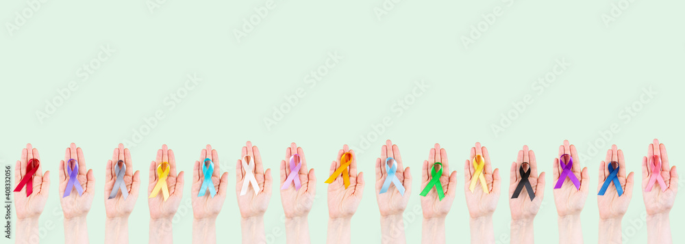 Women's hands hold multicolored ribbons, symbol of the fight against cancer. World cancer day