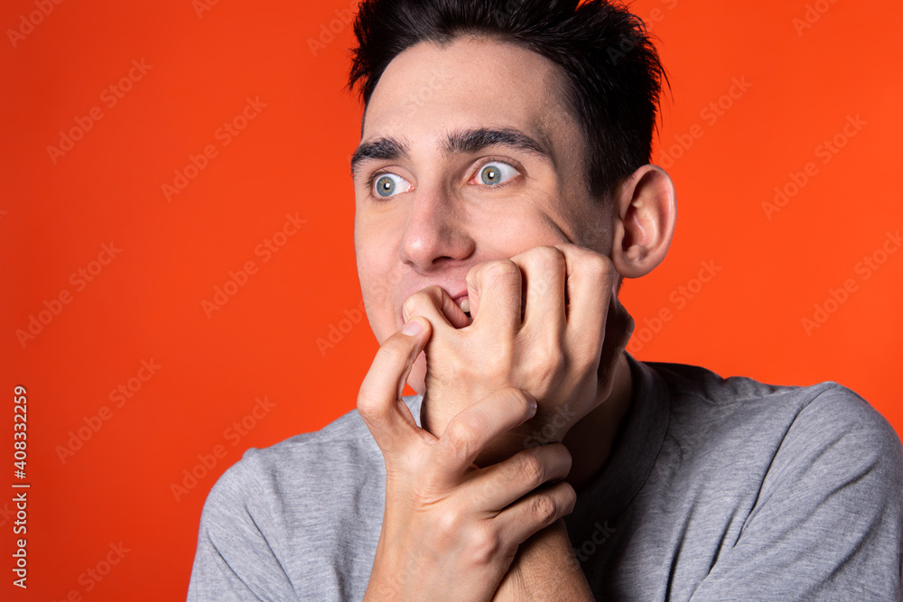 The young man is actively gesturing. Expression of emotions. Blue clothes. Orange background. Point of view. The young man is actively gesturing. Expression of emotions. Blue clothes. Orange background. Point of view.