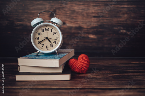 Alarm clock on book stack on wood table. photo