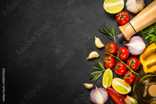 Food cooking background on black stone table. Fresh vegetables, spices, herbs. Ingredients for cooking. Top view with copy space.