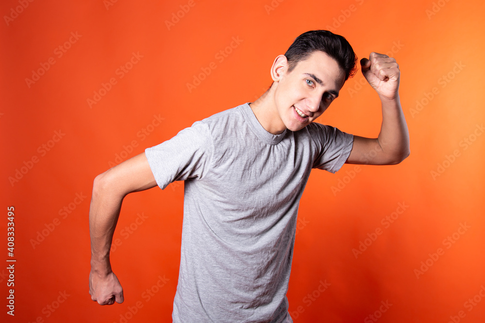 The young guy is happy about the victory. Feelings and emotions. Orange background.