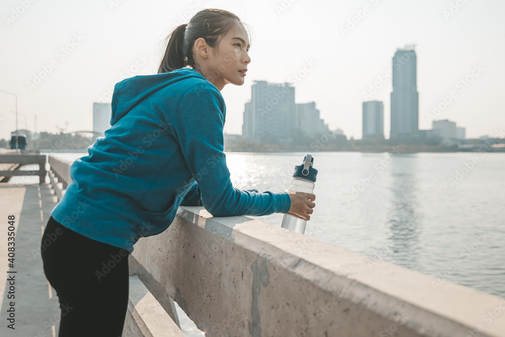 woman athlete thirsty takes a break. she hold water bottle after running.