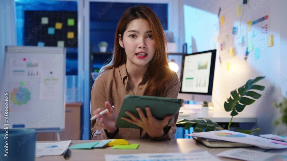 Asia businesswoman social distancing in new normal for virus prevention looking at camera presentation to colleague about plan in video call while work in office night. Lifestyle after coronavirus. Asia businesswoman social distancing in new normal for virus prevention looking at camera presentation to colleague about plan in video call while work in office night. Lifestyle after coronavirus.