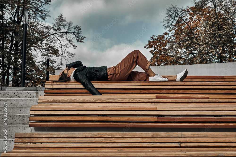 The girl lies on a wooden bench. Photo session in the city. The consequences of the party. The girl lies on a wooden bench. Photo session in the city. The consequences of the party.