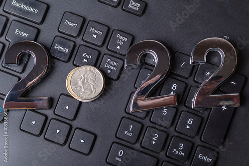 black keyboard close-up. on it are laid out numbers of metal 2022 in the center of the coin 0.25 dallar. photo