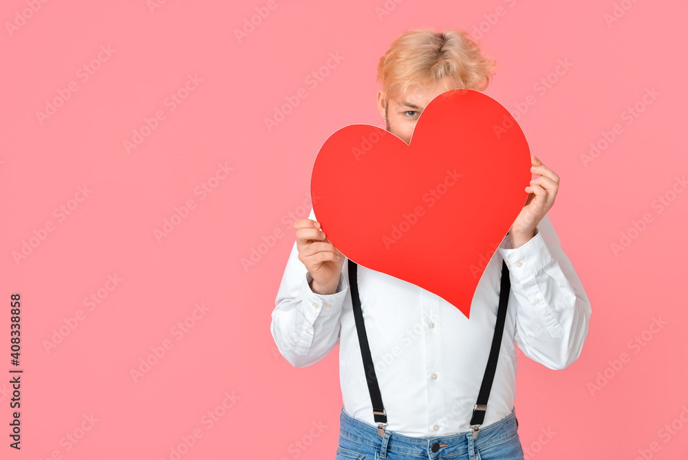 Handsome man with big red heart on color background Handsome man with big red heart on color background