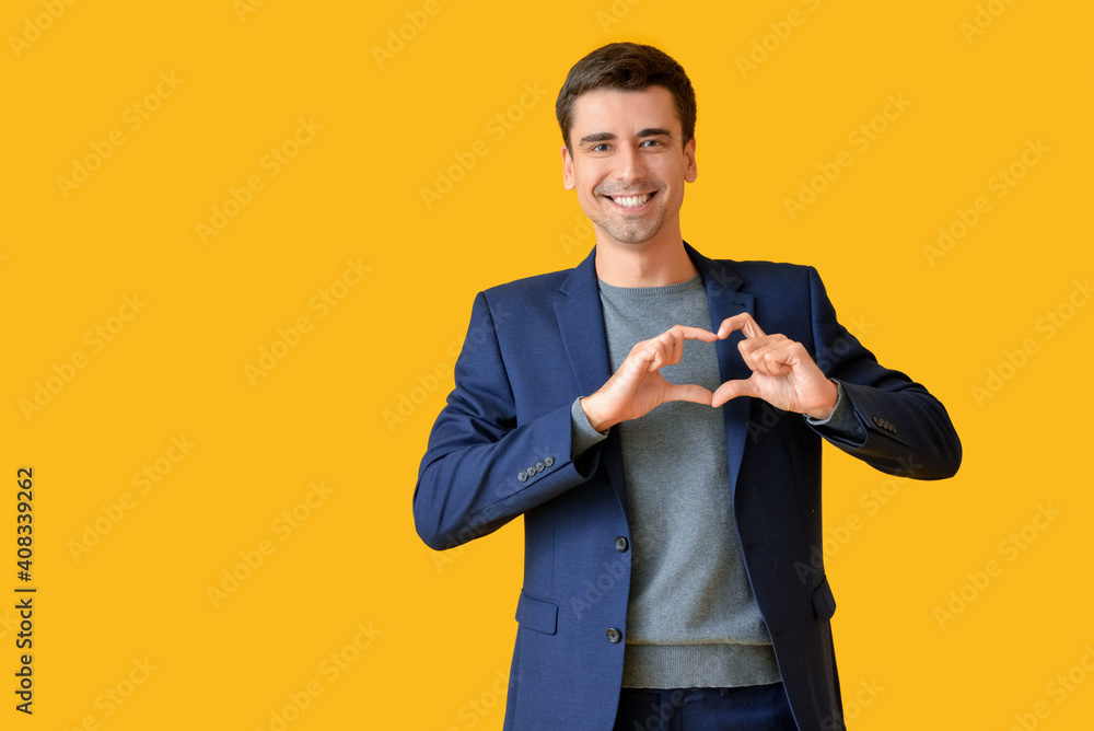 Handsome man making heart with his hands on color background Handsome man making heart with his hands on color background