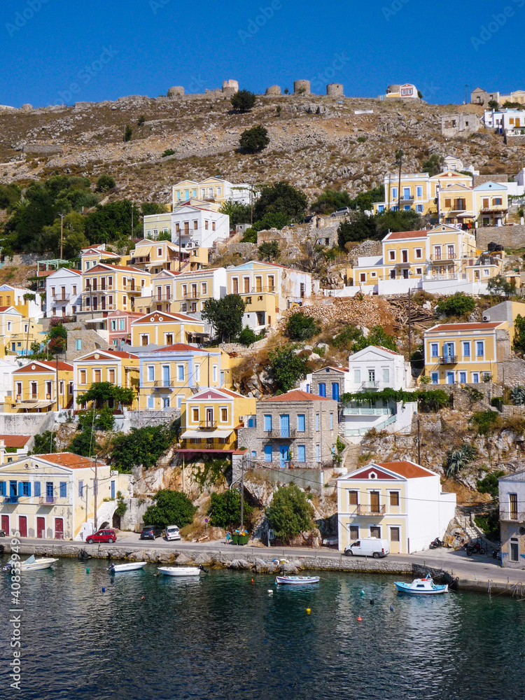 houses, buildings and castle with yachts and boats in the  port town of Simi a Greek island in the Aegean