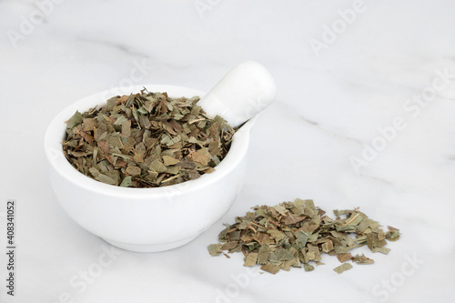 Ash herb leaves in a mortar with pestle used in herbal medicine to treat fever, arthritis, constipation, gout, fluid retention and bladder problems. Fraxinus exelsior. On marble. photo
