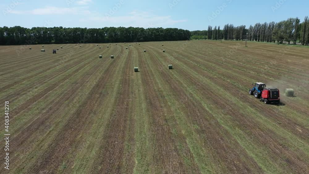 A round baler discharges a fresh wheat bale during harvesting aerial view. A round baler discharges a fresh wheat bale during harvesting aerial view.