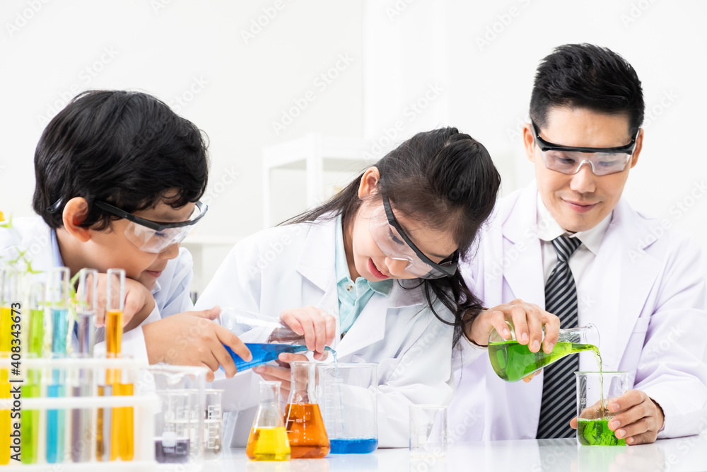 Young Asian kids wearing white scientist gown and do chemical test tube while study, learning in science classroom with teacher. Young children education concept by experiment, fun and enjoy classroom Young Asian kids wearing white scientist gown and do chemical test tube while study, learning in science classroom with teacher. Young children education concept by experiment, fun and enjoy classroom