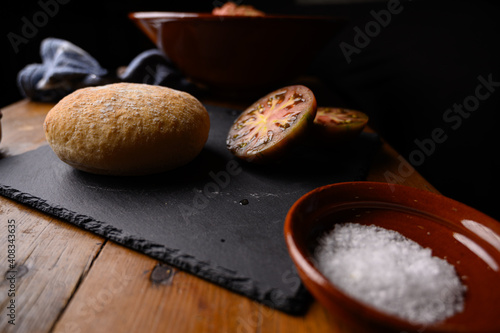 Bodegón con tomate pan y sal en mesa de madera y recipiente de barro