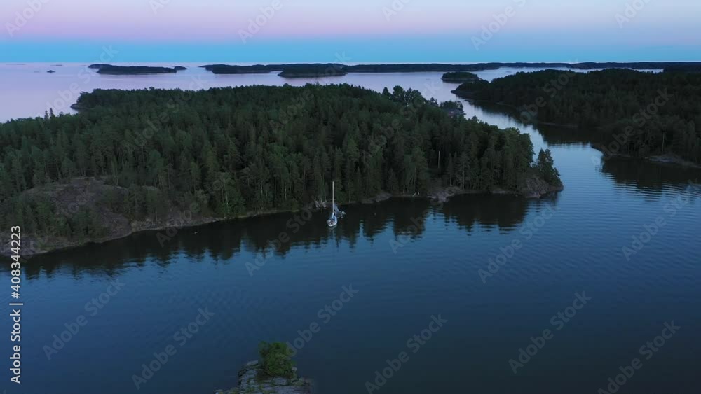 Aerial view around a sailboat anchored at a island pier, vibrant dusk sky - orbit, drone shot Aerial view around a sailboat anchored at a island pier, vibrant dusk sky - orbit, drone shot