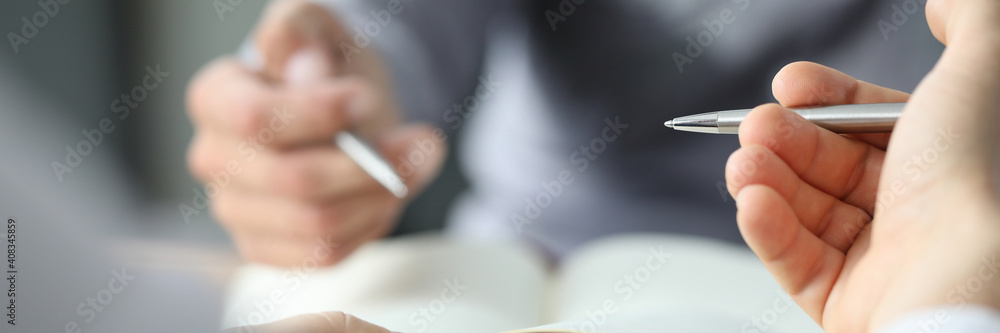 Close up of male hands holding sheet of paper with pen while sitting at the desk in the office. Work and business concept - obrazy, fototapety, plakaty 