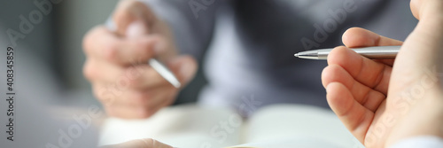 Close up of male hands holding sheet of paper with pen while sitting at the desk in the office. Work and business concept photo