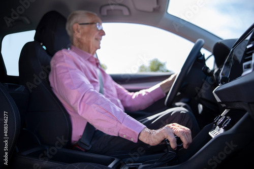 Interior Shot Of Smiling Senior Man Enjoying Driving Car With Hand On Gear Shift © Daisy Daisy