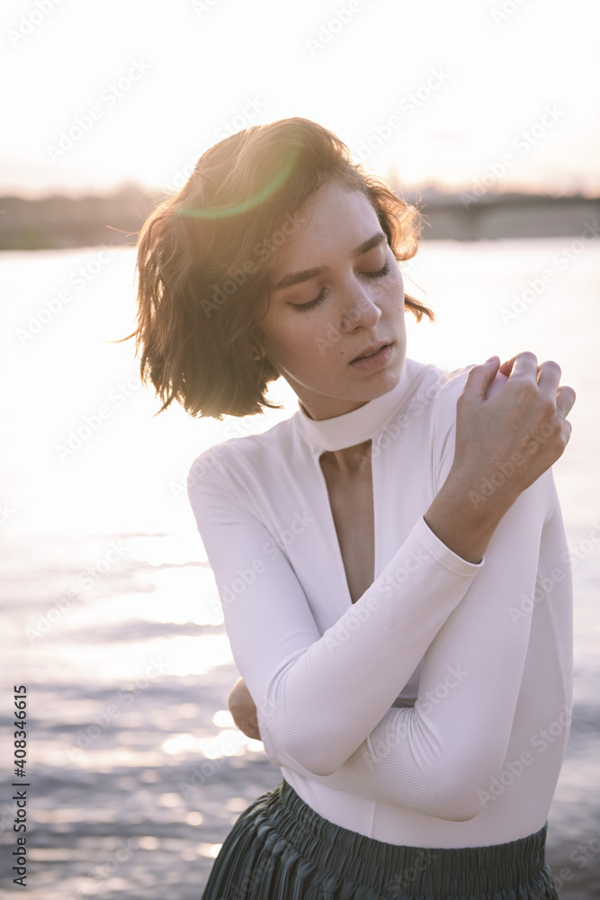 young woman posing and dancing near beach at sunset