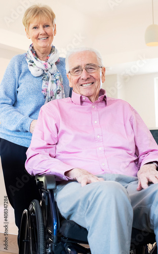 Portrait Of Senior Couple With Husband In Wheelchair At Home